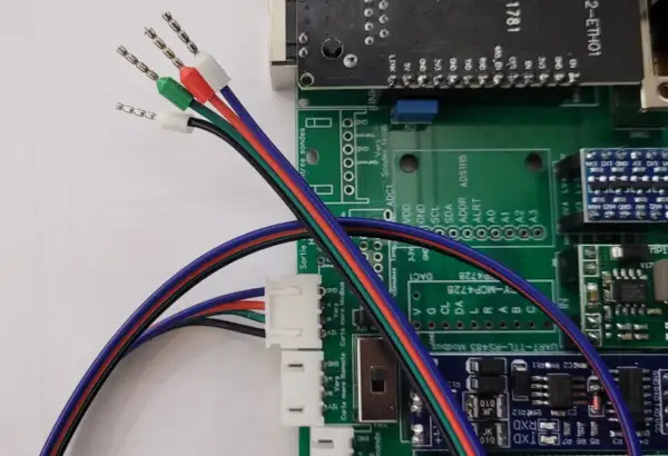 Fils multicolores, dont un fil noir et blanc 12V, connectés à une carte électronique.
