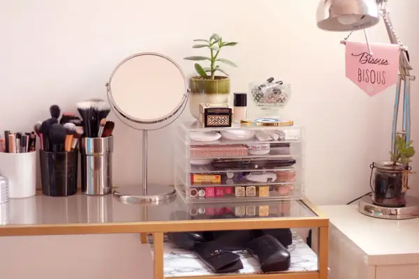 Coiffeuse organisée avec miroir, pinceaux, maquillage et plante.