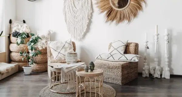Salon au thème bohème chic avec fauteuils en rotin, coussins graphiques, macramé mural et bougeoirs sculptés.
